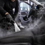 Professional car detailing technician deep cleaning vehicle seats and interior to remove smoke and musty odors