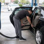 Customer vacuuming the interior of a freshly washed vehicle at a professional car wash